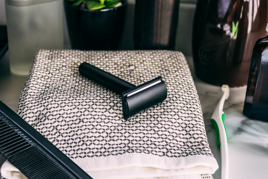A matte black safety razor resting on a folded towel on a bathroom counter
